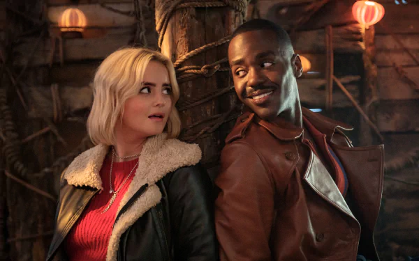 HD wallpaper from Doctor Who (2023) featuring Ncuti Gatwa and a female costar in a warmly lit, rustic setting.