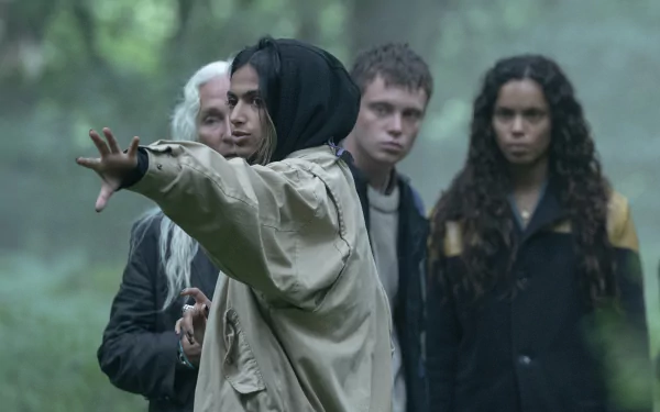 HD desktop wallpaper from the 2024 movie The Watchers, depicting four people standing in a foggy forest, one person gesturing ahead while the others observe.