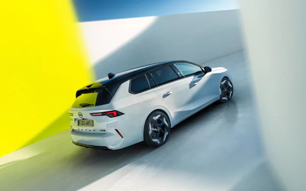 HD desktop wallpaper featuring a sleek white Opel Astra GSe, viewed from the rear, driving through a minimalistic, brightly lit space with contrasting yellow and white walls.