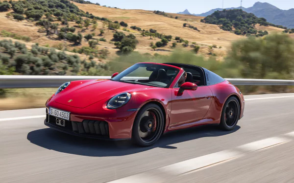 HD desktop wallpaper featuring a red Porsche 911 Targa 4 GTS driving on a scenic road with rolling hills and trees in the background.