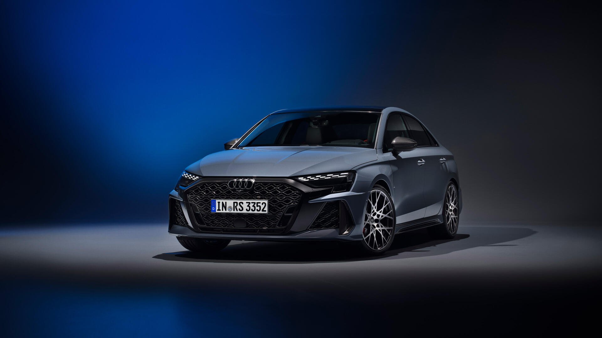 An Audi RS3 Sedan stands prominently against a dark background, showcasing its sleek design and dynamic lines in this stunning 4K Ultra HD desktop wallpaper.