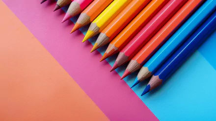 A vibrant arrangement of colored pencils on a backdrop of pink and blue, creating a visually appealing HD desktop wallpaper and background.