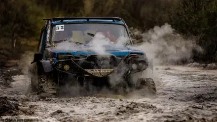 A rugged off-road vehicle splashes through muddy terrain, surrounded by billowing steam, showcasing the thrill of adventure and the challenge of extreme conditions in this HD desktop wallpaper.