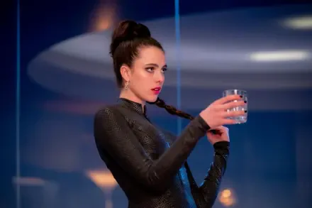 A stylish HD wallpaper featuring Margaret Qualley in a striking pose, holding a glass, from the movie The Substance. The backdrop enhances the modern aesthetic.