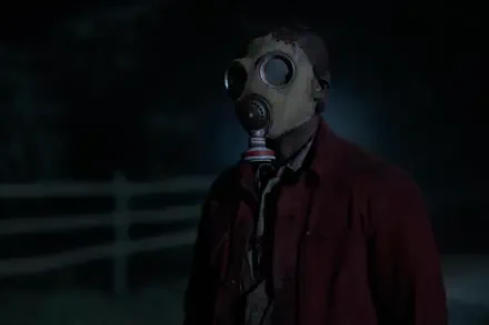 A mysterious figure in a gas mask stands in a dark setting, embodying the eerie atmosphere of the TV show Teacup (2024). Captured in stunning 8K Ultra HD detail.