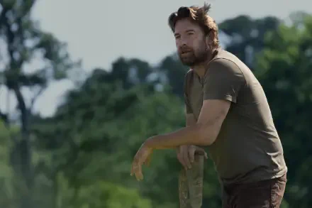 Scott Speedman gazes thoughtfully while leaning on a post in a lush, green landscape from the TV show Teacup (2024), captured in stunning 8K Ultra HD resolution.
