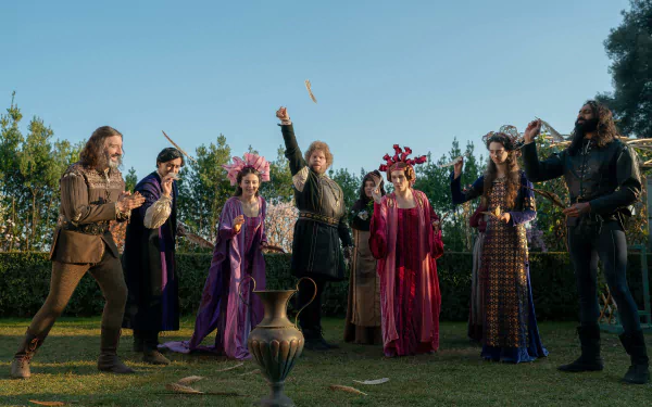 A vibrant scene from the TV show The Decameron, featuring a group of characters in historic costumes, joyfully interacting in a lush outdoor setting. مناسب كشاشة خلفية بدقة عالية.