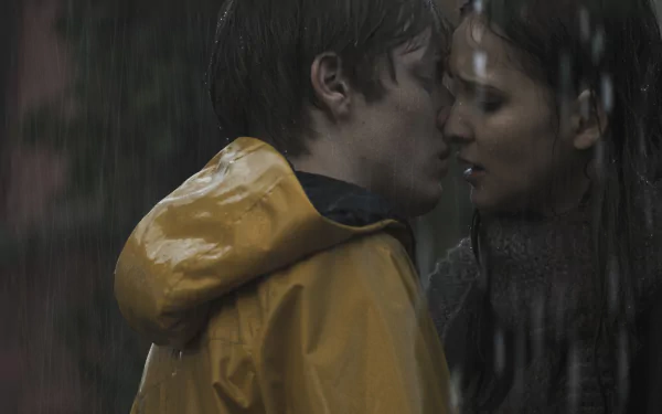 A captivating scene from the TV show Dark, featuring Louis Hofmann and Lisa Vicari sharing a tender moment in the rain, set against a dramatic backdrop. HD wallpaper.