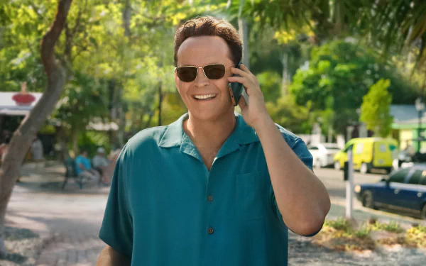 A vibrant HD wallpaper featuring Vince Vaughn in Bad Monkey, smiling and talking on the phone against a lush, green backdrop.