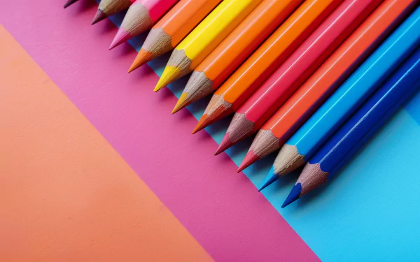 A vibrant arrangement of colored pencils on a backdrop of pink and blue, creating a visually appealing HD desktop wallpaper and background.