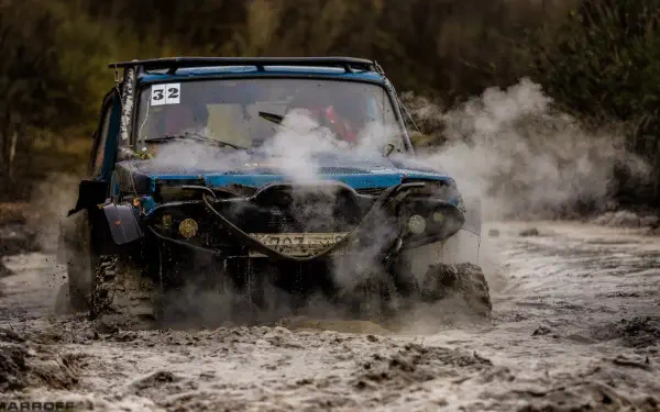 A rugged off-road vehicle splashes through muddy terrain, surrounded by billowing steam, showcasing the thrill of adventure and the challenge of extreme conditions in this HD desktop wallpaper.