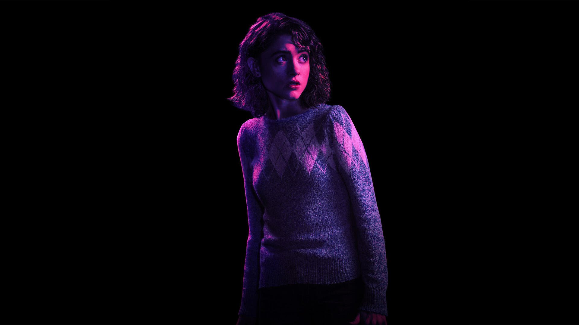 A striking HD image of Natalia Dyer as Nancy Wheeler from Stranger Things, featuring dramatic lighting against a dark background.