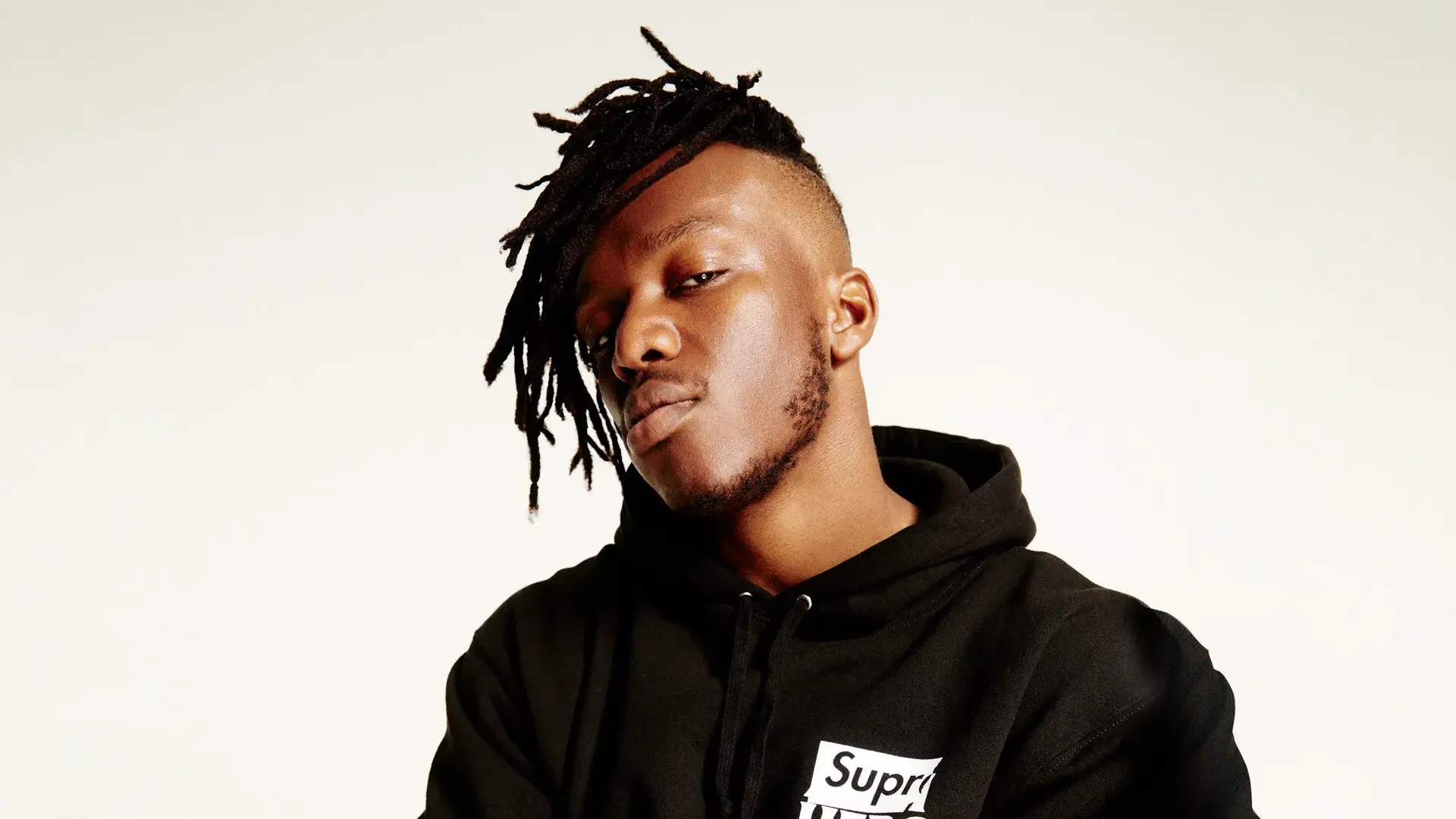 A high-definition desktop wallpaper featuring KSI, showcasing his distinctive style with dreadlocks and a confident expression, set against a simple background.