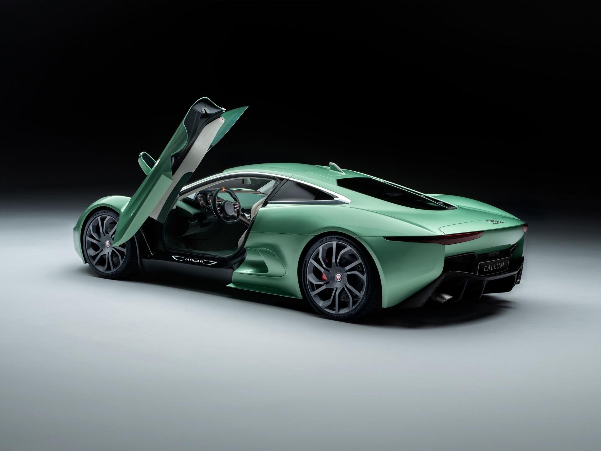 HD desktop wallpaper featuring a sleek green Jaguar C-X75 luxury car with its door open, showcasing its futuristic design and elegance.