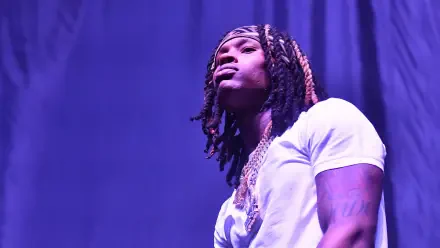 A HD wallpaper featuring rapper King Von, showcasing his signature style and presence on stage with a dramatic purple backdrop.