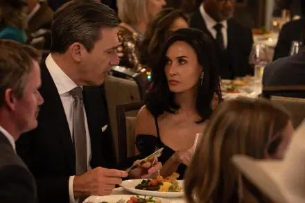 A scene from the TV show Landman, featuring Demi Moore at a formal dinner, engaged in conversation with a man. The setting is upscale, surrounded by other diners.