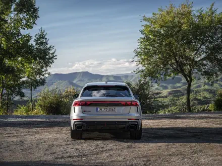 A rear view of an Audi RS Q8 parked in a scenic landscape, surrounded by lush greenery and mountains under a clear sky. A stunning 4K Ultra HD background for any desktop.