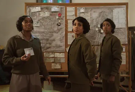 A dramatic scene from the movie The Six Triple Eight, featuring three women in period attire, standing in front of a detailed map with notes and photographs, set against a historic backdrop.
