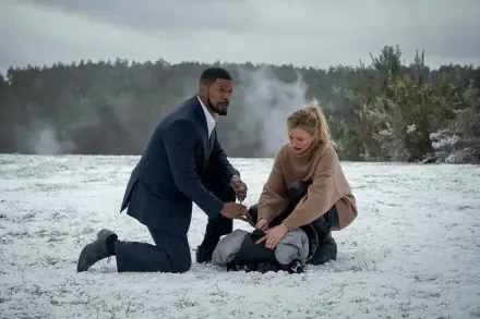 Cameron Diaz and Jamie Foxx in a tense scene from the movie Back in Action, kneeling in the snow as they assist a figure on the ground, framed by a dramatic winter landscape.