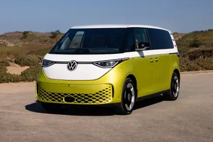 An electric Volkswagen ID. Buzz parked on a sunny, open road, showcasing its vibrant green and white design in a scenic outdoor setting.