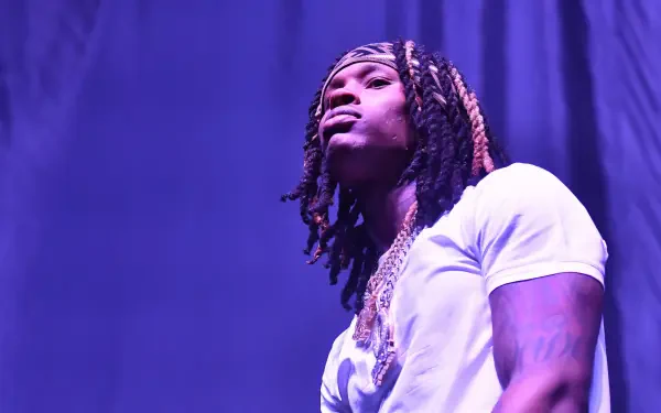 A HD wallpaper featuring rapper King Von, showcasing his signature style and presence on stage with a dramatic purple backdrop.