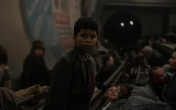 A scene from the movie Blitz (2024) featuring Elliott Heffernan, showing a young character in a crowded underground setting, capturing a moment of tension and atmosphere. 