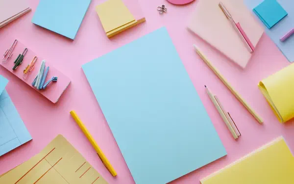 A vibrant arrangement of cute stationery items on a pink background, including colorful notepads, pens, and clips, designed as a stunning 4K Ultra HD PC desktop wallpaper.