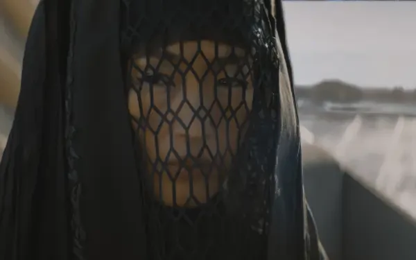 A character from the TV show Dune Prophecy gazes intently, shrouded in a dark veil, set against a dramatic desert backdrop, creating an intriguing atmosphere for a HD wallpaper.