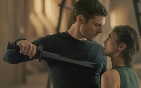 A captivating moment from the TV show Dune Prophecy, featuring intense characters portrayed by Sarah-Sofie Boussnina and an imposing figure, set against a dramatic backdrop.