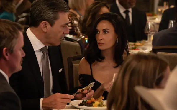 A scene from the TV show Landman, featuring Demi Moore at a formal dinner, engaged in conversation with a man. The setting is upscale, surrounded by other diners.