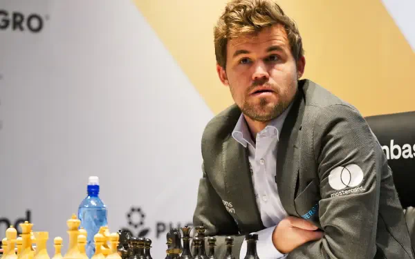 Magnus Carlsen ponders his next move at a chess tournament, surrounded by pieces on a board. This dynamic image serves as a vibrant 4K Ultra HD desktop wallpaper for sports and chess enthusiasts.