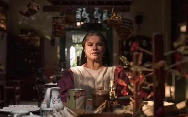 A character from the TV show One Hundred Years of Solitude sits thoughtfully in a richly decorated interior, captured in stunning 8K Ultra HD.