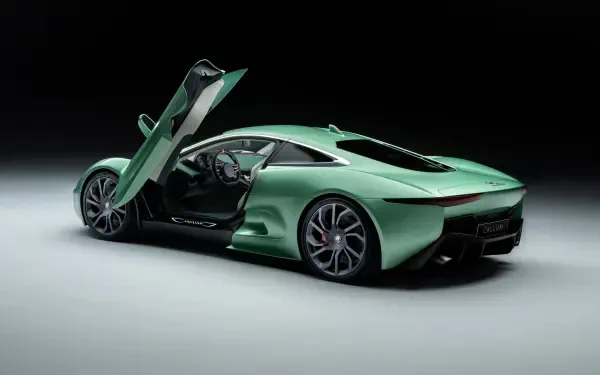 A sleek Jaguar C-X75 luxury car in a striking green color, features upward-opening doors, set against a minimalist black background, ideal for a stunning HD desktop wallpaper.