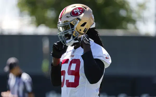 San Francisco 49ers linebacker De'Vondre Campbell adjusts his helmet during practice, embodying the intensity of NFL football in this dynamic HD desktop wallpaper.