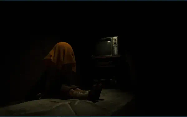 A dark scene from the video game The Cabin Factory, featuring a figure draped in a yellow cloth sitting by an old television, creating an eerie atmosphere for an HD PC wallpaper.