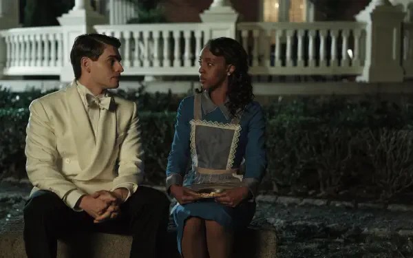 A scene from the movie The Six Triple Eight featuring Kerry Washington and Gregg Sulkin. The two characters sit together, engaged in conversation, against a softly lit background.