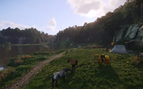 A serene landscape from Kingdom Come: Deliverance II, featuring horses grazing near a river, surrounded by lush greenery and a backdrop of hills under a blue sky.
