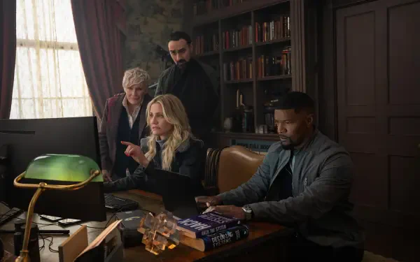 Cameron Diaz and Jamie Foxx appear in a scene from the movie Back in Action, focusing intently at a computer with two others in a well-furnished office setting.