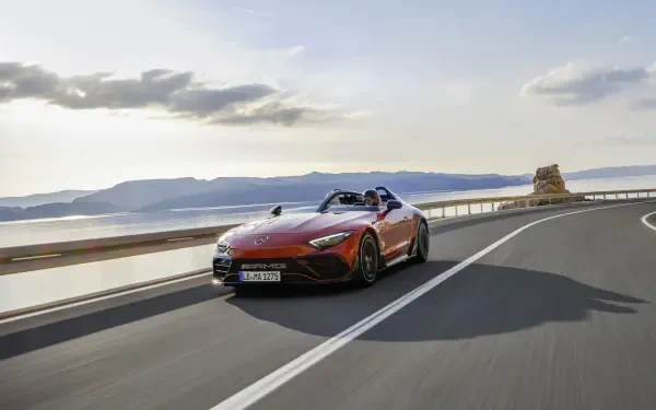 A sleek Mercedes-AMG PureSpeed sports car accelerates along a coastal road under a clear sky, showcasing its power and elegance in vibrant 4K Ultra HD resolution.