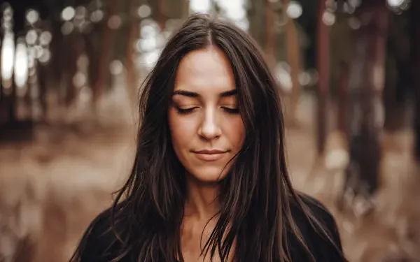 Portrait of a serene woman with closed eyes in a natural forest setting, captured in 4K Ultra HD for a peaceful PC desktop wallpaper.