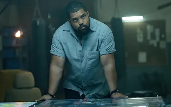 O'Shea Jackson Jr. leans over a table in a dimly lit room, analyzing a scenario in the film Den of Thieves 2: Pantera. This image is a striking 4K Ultra HD desktop wallpaper.