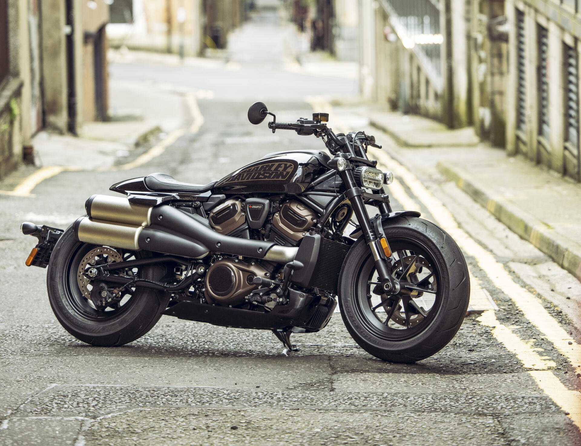 A sleek Harley-Davidson Sportster parked on a quiet street, showcasing its powerful design and chrome accents. This 4K Ultra HD wallpaper captures the bike's striking features.