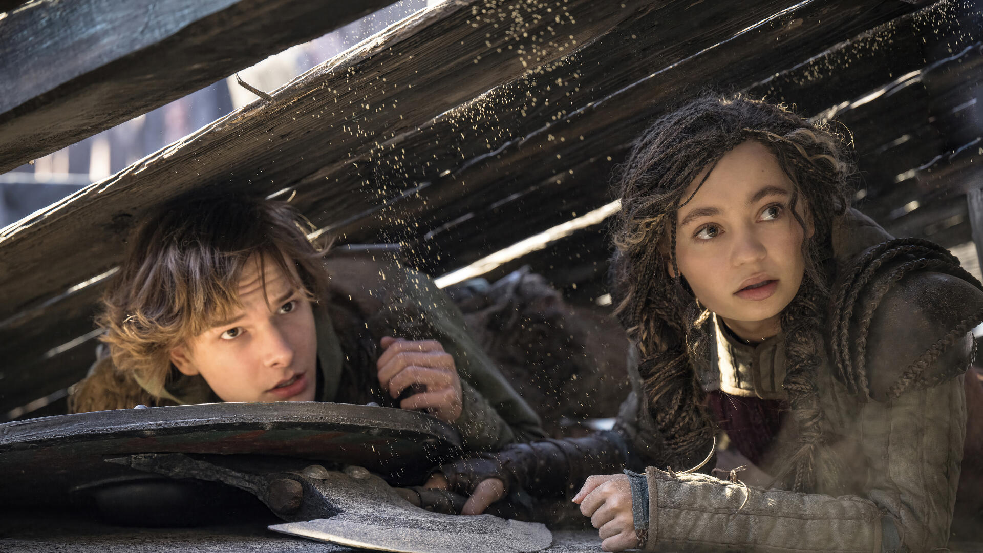 Hiccup and Astrid from How to Train Your Dragon (2025) peering out from under debris, showcasing a moment of tension and adventure in this 4K Ultra HD wallpaper.