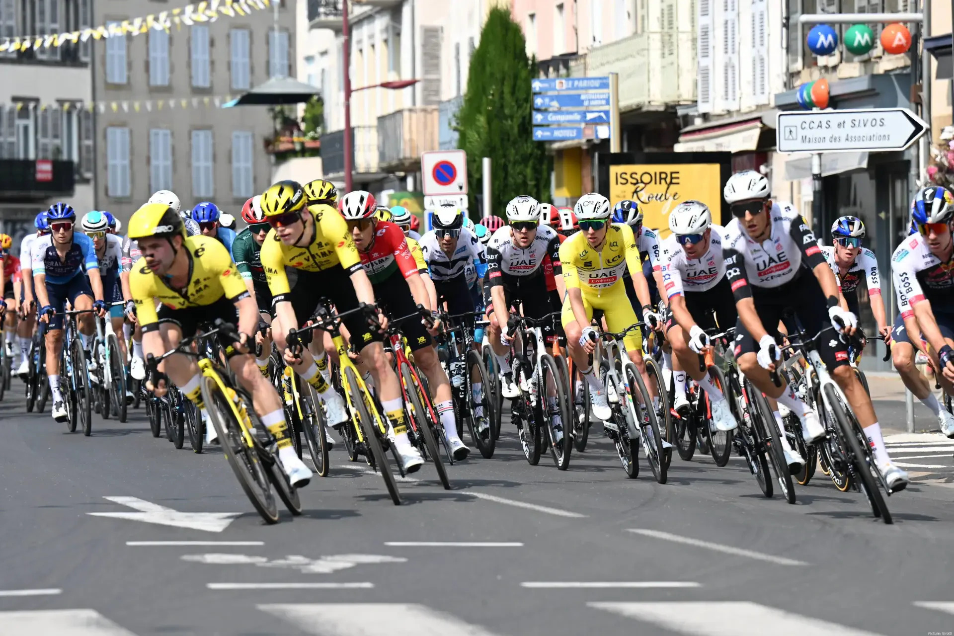 Cyclists race intensely in the Critérium du Dauphiné, with riders tightly packed on city streets in this 4K Ultra HD sports cycling competition wallpaper.