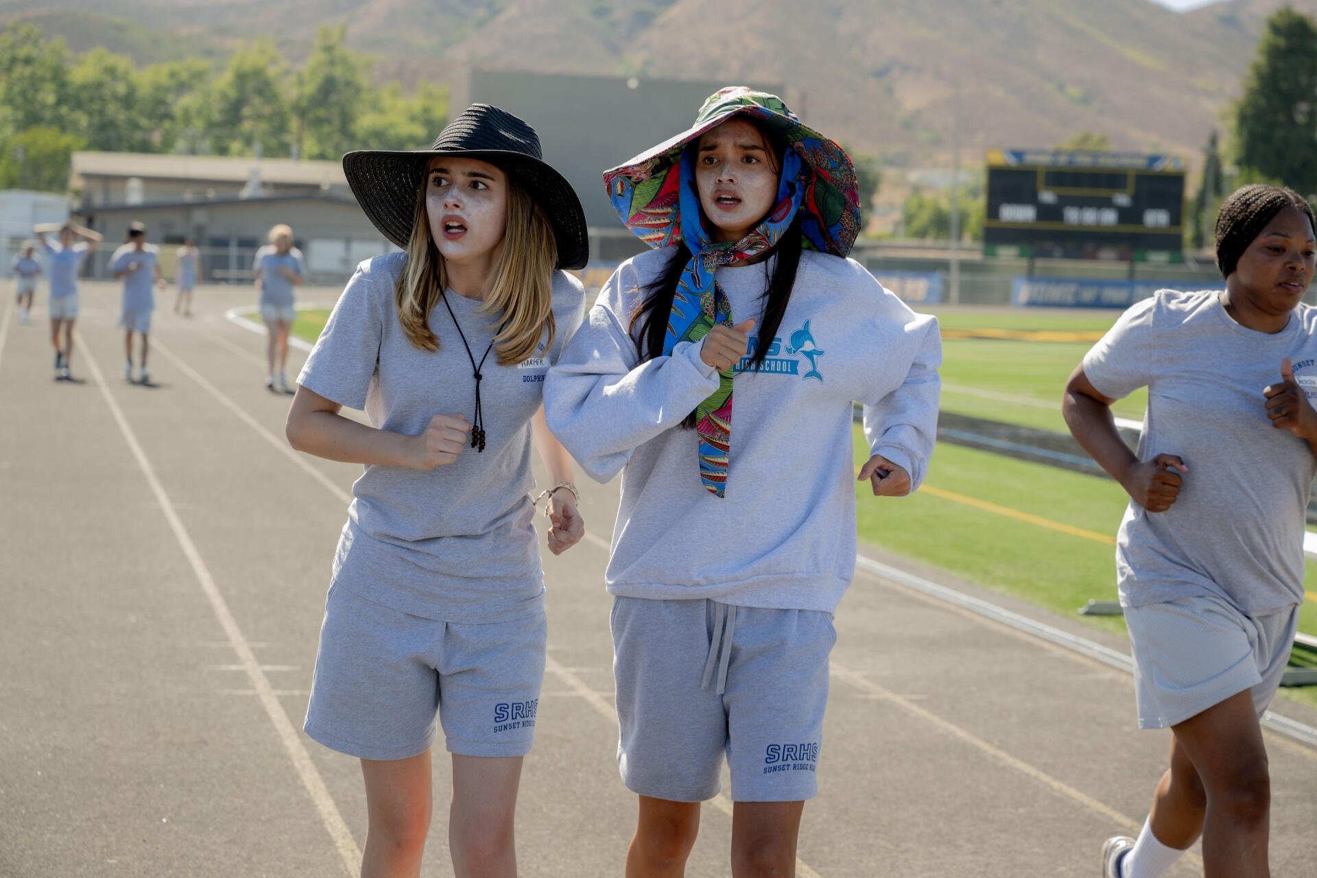 Scene from the movie Freakier Friday showing two characters jogging on a track, featured as an 8K Ultra HD PC desktop wallpaper and background.