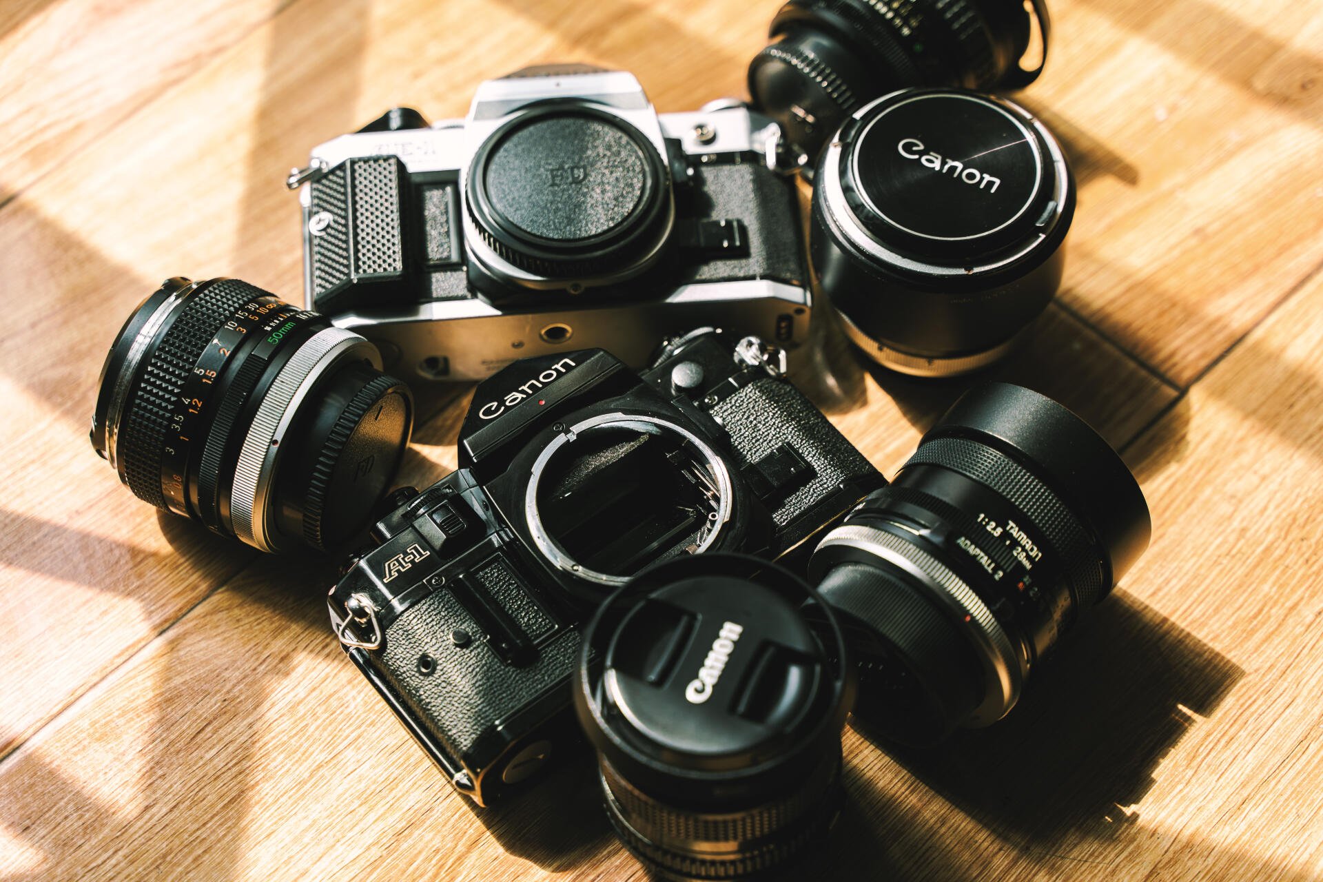 Vintage Canon cameras and lenses arranged on a wooden surface, captured in sharp 4K Ultra HD quality for a striking man-made PC desktop wallpaper.
