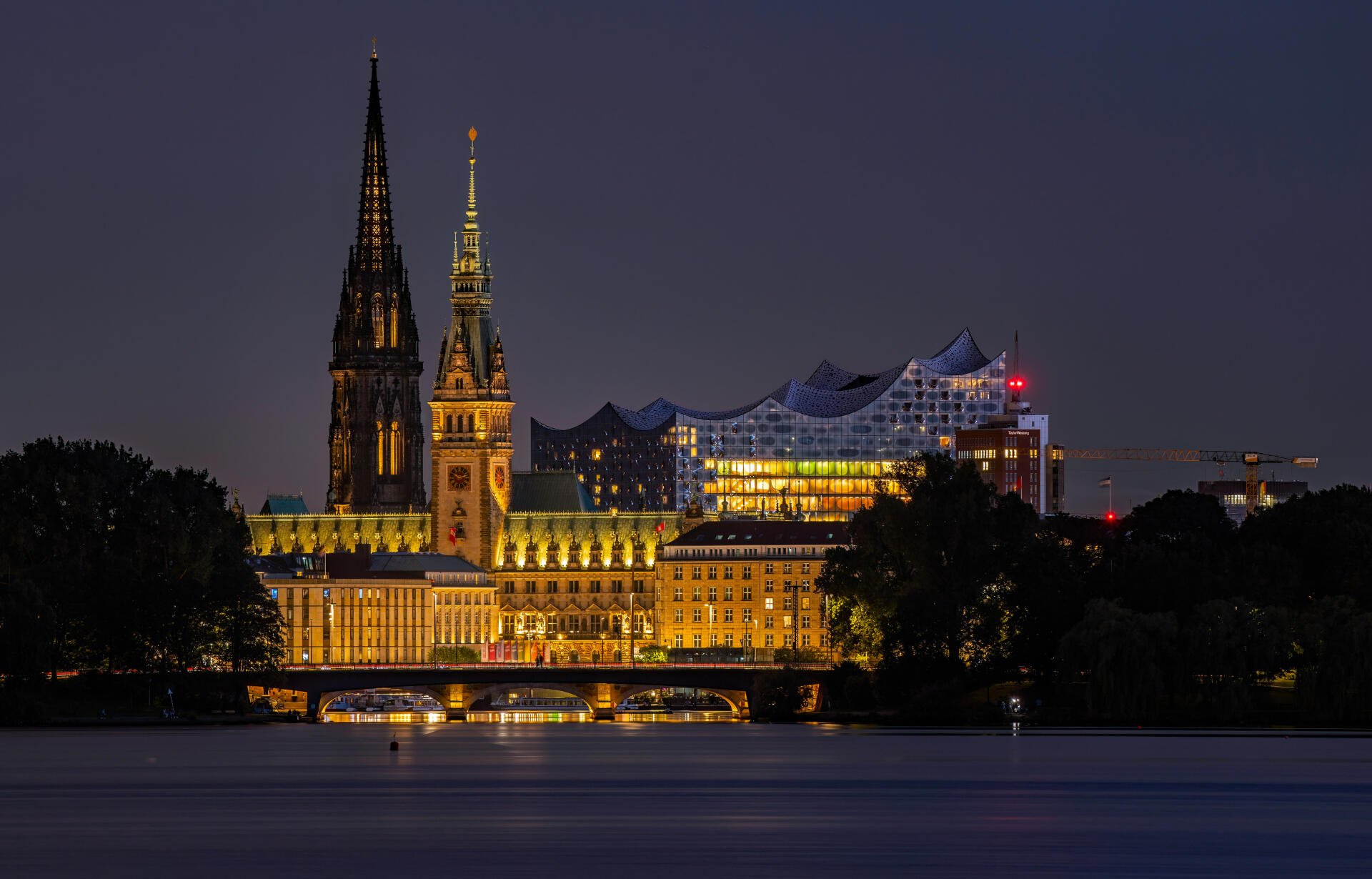 Nighttime view of illuminated historic and modern buildings along the waterfront in Hamburg, Germany, captured in stunning 4K Ultra HD for a desktop wallpaper.