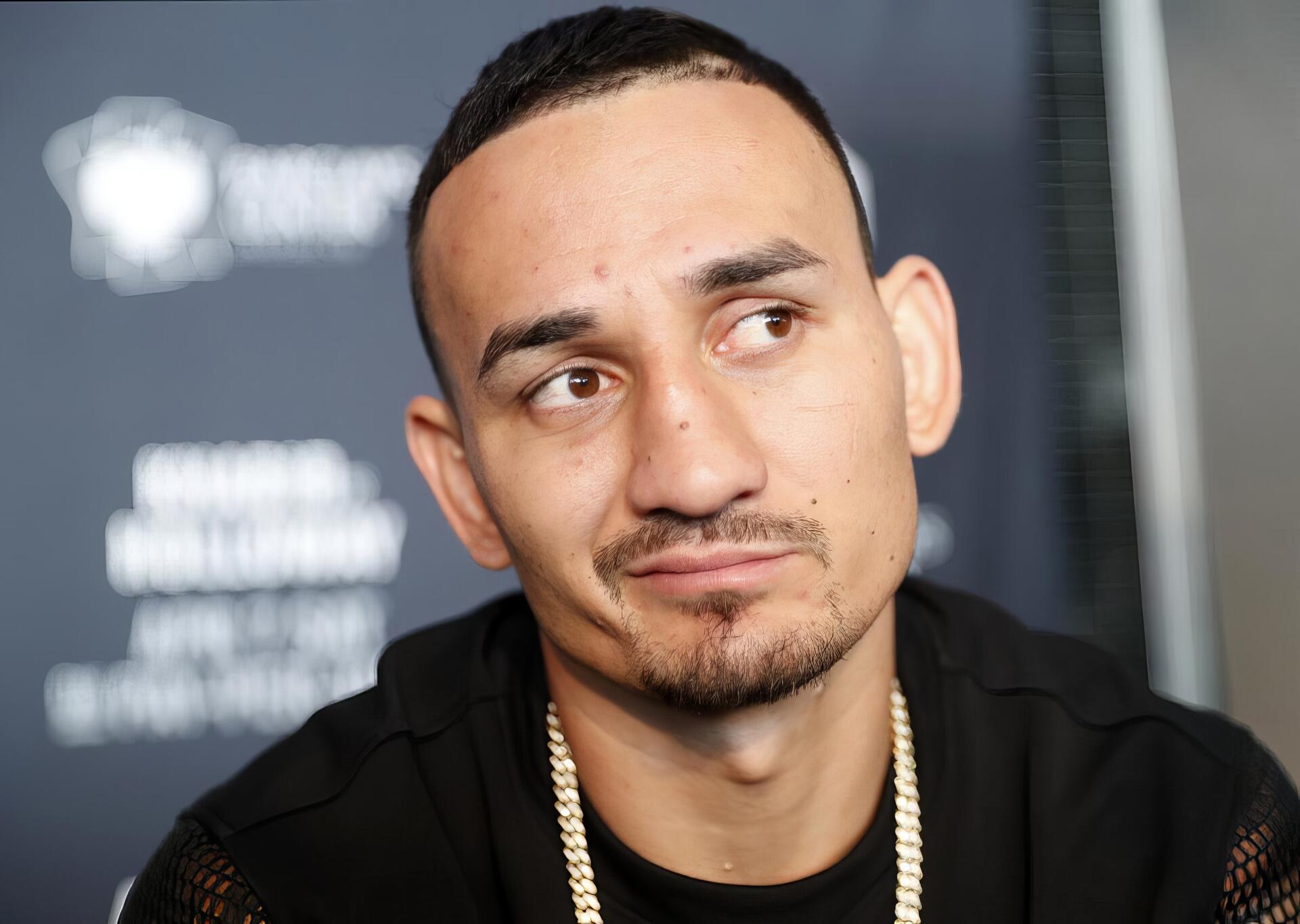 HD PC desktop wallpaper featuring UFC fighter Max Holloway with a thoughtful expression against a blurred event backdrop.