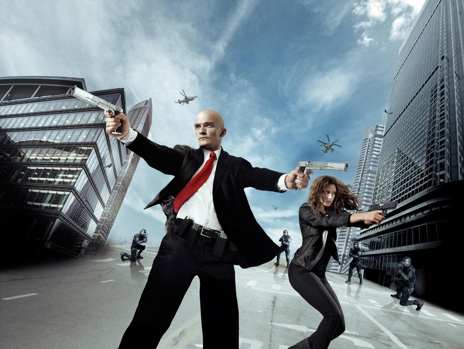 Hit Man — 4K Ultra HD PC desktop wallpaper/background: bald assassin in black suit and red tie and female partner firing pistols between glass skyscrapers, jets streaking across a stormy sky.