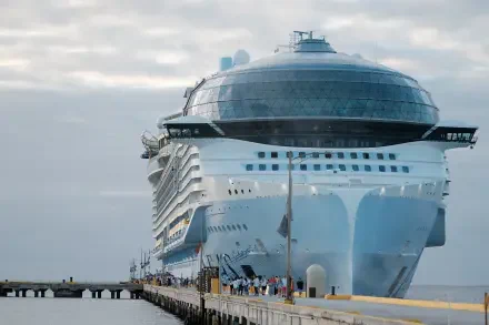 A large Royal Caribbean cruise ship is docked at a pier, showcasing its modern design against a cloudy sky. This 4K Ultra HD image serves as a vibrant desktop wallpaper.